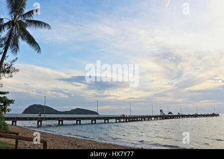 Palm Cove jetty, un palmier sur le sable, un peu de ciel bleu derrière les nuages vaporeux blanc, Double Island au-delà de la jetée, capturé tôt le matin Banque D'Images