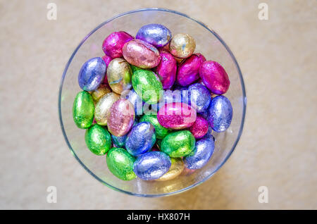 Mini oeufs de Pâques en chocolat emballés dans des emballages d'aluminium de couleur vive dans un vase de verre. Banque D'Images