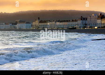 La célèbre ville côtière de Llandudno en Galles du Nord baigné de soleil de l'été le lever du soleil sur la baie que les vagues déferlent sur le rivage Banque D'Images