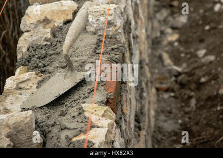Sur le mur de pierre à la truelle, au cours de travaux de construction Banque D'Images
