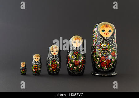 De magnifiques poupées russes d'emboîtement (poupées matriochka) avec blanc, vert et rouge en face de la peinture fond sombre Banque D'Images