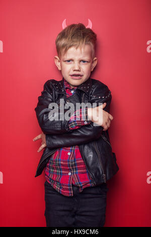 Beau petit diable avec des cornes et la queue. Kid. L'Halloween. Portrait Studio sur fond rouge isolé Banque D'Images