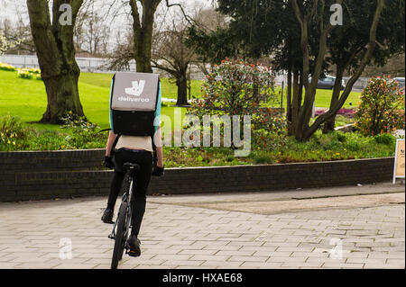 Livraison de nourriture Deliveroo employé homme monté sur un vélo avec un push livraison alimentaire fort sur son dos. Banque D'Images