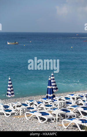 Chaises longues et parasols pliés sur la plage de Nice. Banque D'Images