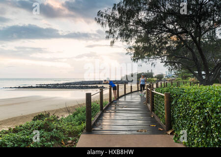 Tôt le matin, les promeneurs sur la promenade de l'Esplanade à plage de Bargara, Bundaberg, Queensland, Australie Banque D'Images