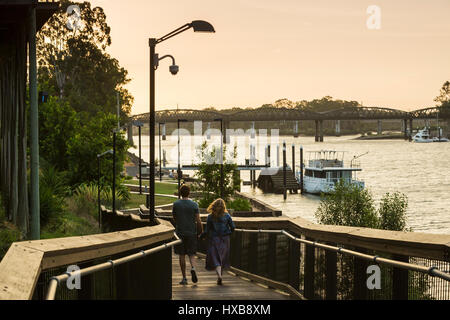 Couple en train de marcher le long de la promenade Riverside au coucher du soleil. Bundaberg, Queensland, Australie Banque D'Images