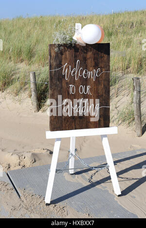 Chevalet en bois avec Bienvenue à notre mariage devant des dunes Banque D'Images