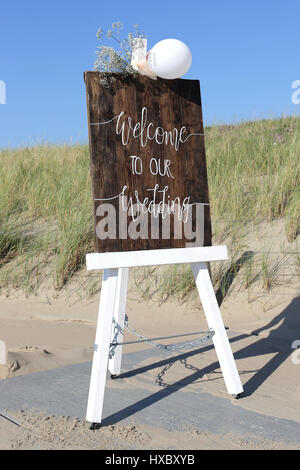 Chevalet en bois avec Bienvenue à notre mariage devant des dunes Banque D'Images