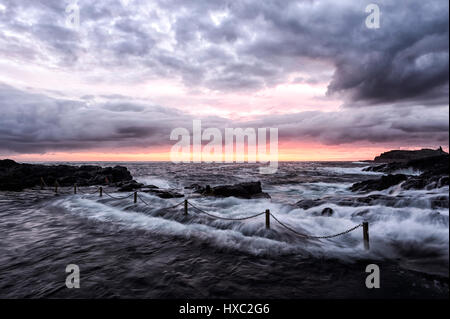 Ethereal le lever du soleil sur une mer formée avec de grosses vagues, de flou et d'un ciel rose, Kiama Rock Pool, Côte d'Illawarra, New South Wales, NSW, Australie Banque D'Images