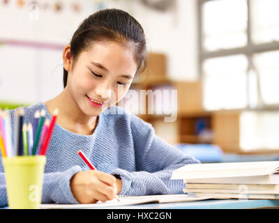 11 ans écolière asiatique fait ses devoirs, heureux et souriant. Banque D'Images