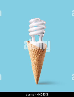 Ampoule fluorescente compacte dans ice cream cone sur fond bleu. La crème glacée faite avec ampoule à économie d'énergie. Concept novateur. Banque D'Images