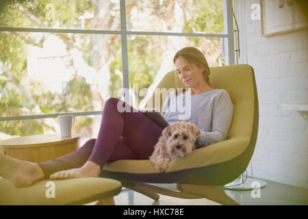 Femme avec chien relaxant, sitting in chair Banque D'Images