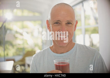 Portrait souriant, confiant mature man drinking smoothie aux fruits sains Banque D'Images