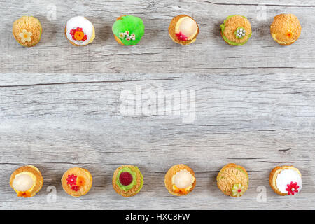 Macarons colorés organiser comme à la ligne supérieure et sur table en bois avec copie espace dans le centre Banque D'Images