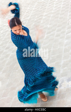 Flou de mouvement d'obturation lente tourné d'une femme danseuse de flamenco espagnol traditionnel de tourner et danser dans une robe à pois bleu Banque D'Images