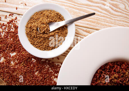 Riz sauvage rouge avec du sésame gomasio assaisonnement dans une assiette blanche sur planche de bois Banque D'Images