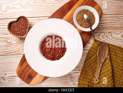 Riz sauvage rouge avec du sésame gomasio assaisonnement dans une assiette blanche sur planche de bois Banque D'Images