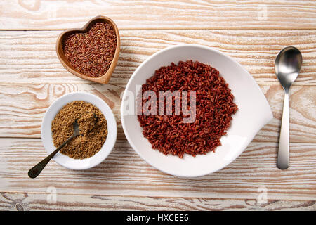 Riz sauvage rouge avec du sésame gomasio assaisonnement dans une assiette blanche sur planche de bois Banque D'Images