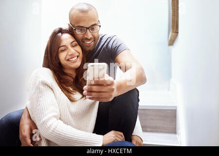 Smiling couple avec téléphone appareil photo en prenant les escaliers selfies Banque D'Images