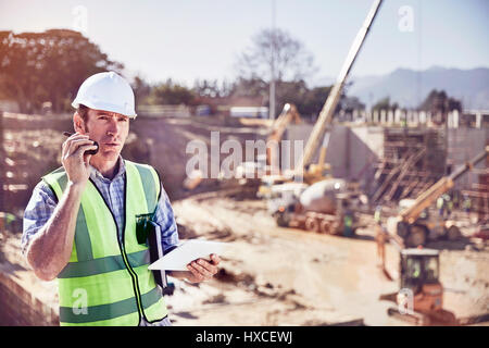 Travailleur de la construction foreman en conversation sur talkie walkie à sunny construction site Banque D'Images