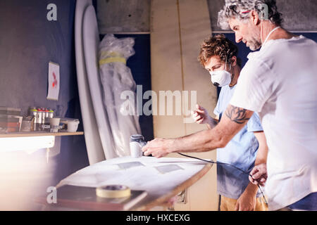 Les concepteurs de surf hommes portant des masques de protection de surf dans l'atelier de ponçage Banque D'Images