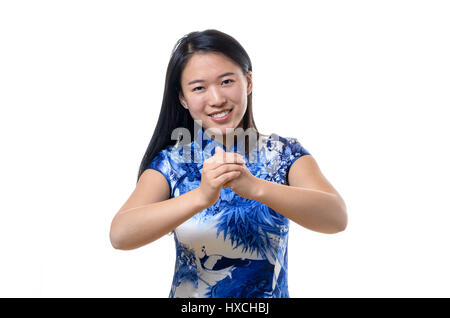 Jeune femme chinoise sincère souriant en costume traditionnel offrant une nouvelle année salutations à l'afficheur des gestes avec ses mains, Close up isolated on whit Banque D'Images