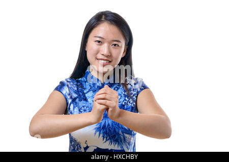 Jeune femme chinoise sincère souriant en costume traditionnel offrant une nouvelle année salutations à l'afficheur des gestes avec ses mains, Close up isolated on whit Banque D'Images