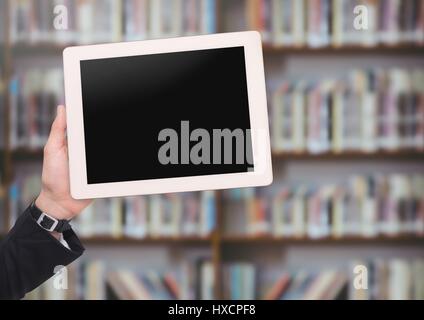 Digital composite de mans hand holding tablet in Library Banque D'Images