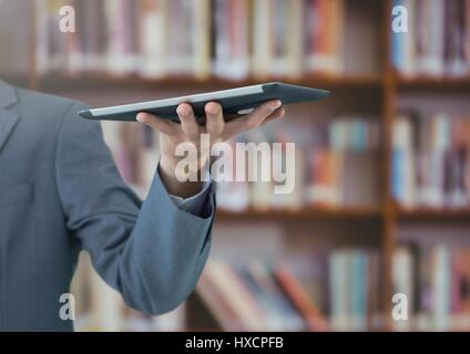 Digital composite de mans hand holding tablet in Library Banque D'Images