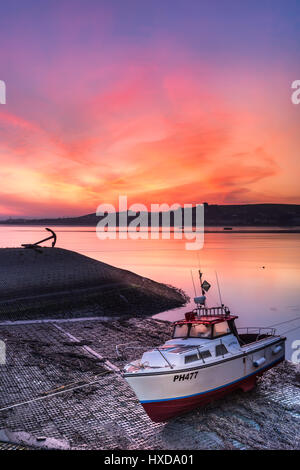 Le ciel devient rose sur la rivière Torridge, comme le soleil se lève à l'aube derrière Instow, illuminant un bateau amarré sur le quai à Appledore dans le Nord du Devon. Banque D'Images