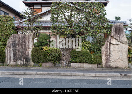 Kyoto, Japon. Grosses pierres et arbustes taillés forment le mur d'un jardin privé dans un quartier de banlieue Banque D'Images