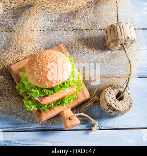 Burger fait maison avec des poissons et légumes sur filet de pêche Banque D'Images