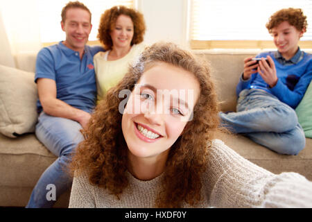 Portrait of a young girl en tenant avec les parents selfies en arrière-plan Banque D'Images