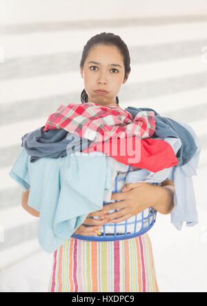 Fatigué de colère femme avec panier de blanchisserie contre l'arrière-plan lumineux Banque D'Images