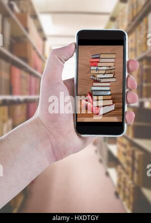 Digital composite de pair avec phone montrant pile contre livre bookshelfs floue Banque D'Images