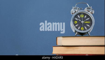 Digital composite de pile de livres avec réveil contre fond bleu Banque D'Images