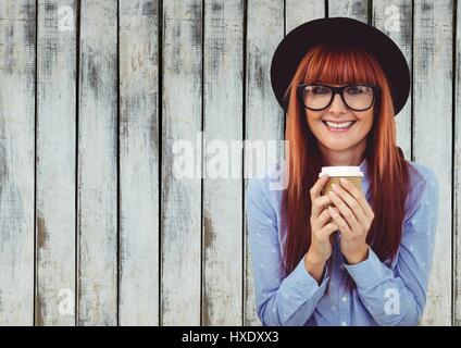 Digital composite of Woman in hat with coffee cup contre le panneau de bois Banque D'Images