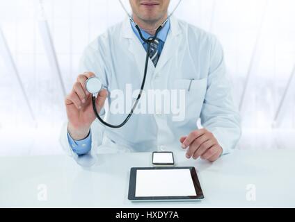 Digital composite of Doctor with stethoscope et périphériques à 24 contre la fenêtre floue Banque D'Images