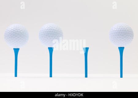 Balles de golf blanc et bleu tés sur le fond blanc. Funny golf concept. Banque D'Images