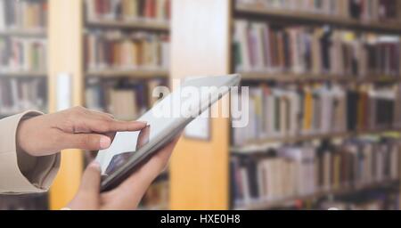 Digital composite de mans hands touching tablet in Library Banque D'Images