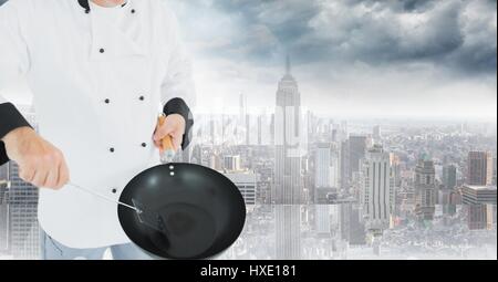 Digital composite de chef avec wok contre skyline floue Banque D'Images