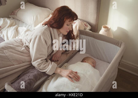 Portrait de mère regardant bébé endormi dans un lit bébé Banque D'Images