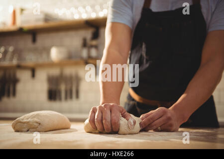 Mid section of male chef de cuisine commerciale dans la pâte à pétrir Banque D'Images