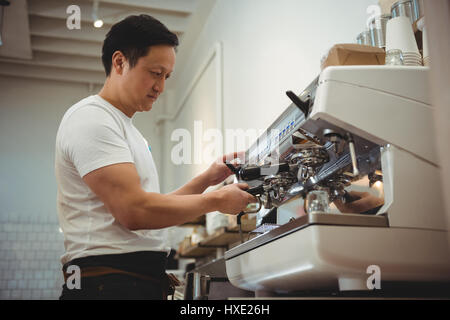 Vue de côté à l'aide d'une machine à expresso barista mâle in cafe Banque D'Images