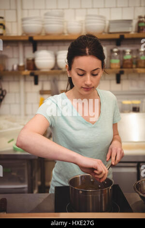 Jeune femme chef de cuisine commerciale dans la cuisson des aliments Banque D'Images
