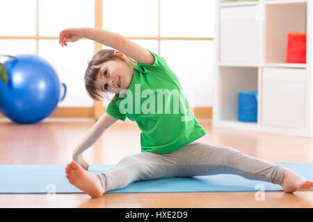 Sportive kid girl doing gymnastic à la maison Banque D'Images