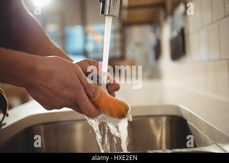Close-up of chef carotte laver sous le robinet de cuisine commerciale Banque D'Images