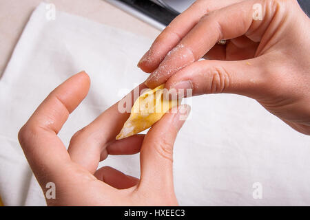 Vue rapprochée de woman's hands la préparation pour la cuisine vareniki, boulettes, pierogi avec du fromage cottage ou une pâte alimentaire traditionnelle ukrainienne. Pi Matériel roulant Banque D'Images