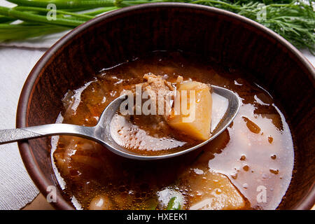 Vue rapprochée de la plaque d'argile et une cuillère à soupe de betteraves rouges ou borsch. Le bortsch ukrainien soupe à la tomate sur fond de bois. Banque D'Images