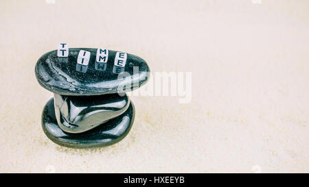 Le concept du temps.TEMPS lettres cube de pierre noire sur fond de sable écrit Banque D'Images